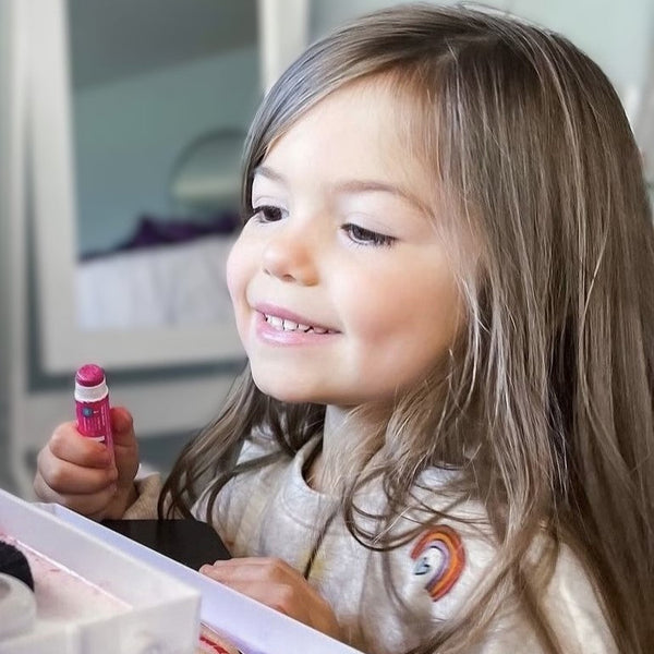 Young girl holding a pink lipstick with a blurred background